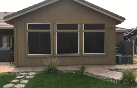 After: dark solar screens on the rear windows of a stucco home